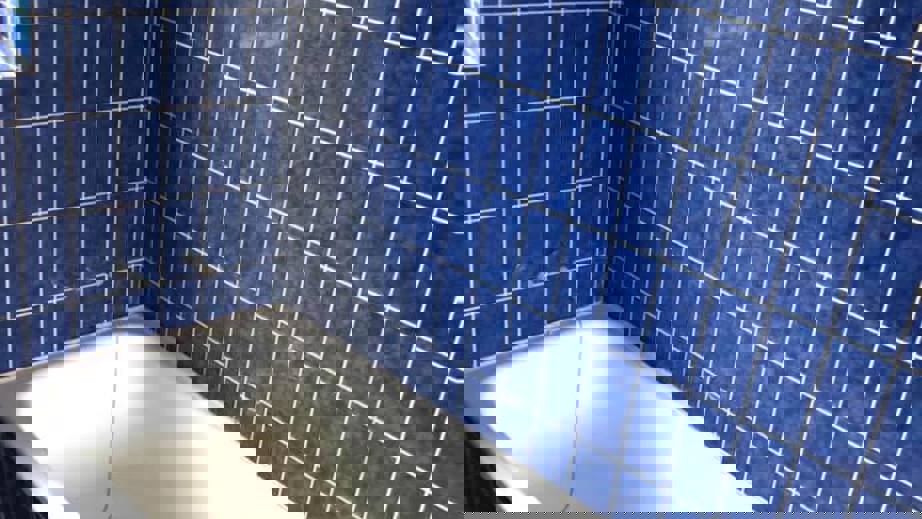 Badeværelse med hvidt badekar omgivet af klassiske blå vægfliser fra gulv til midt på væggen.