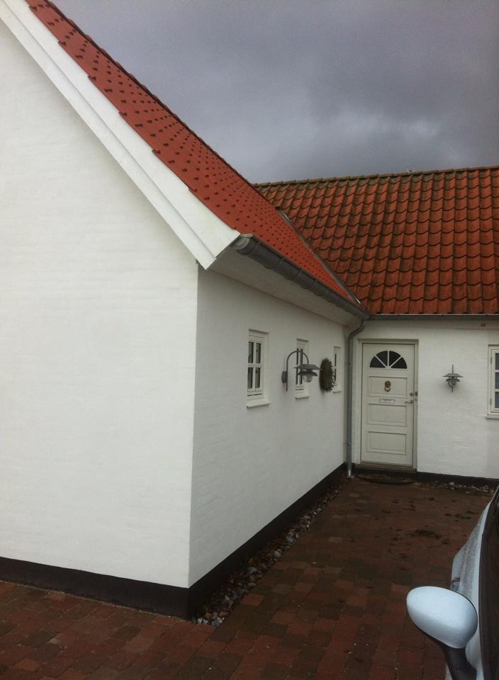 Tegltag på et hvidt hus set fra siden.