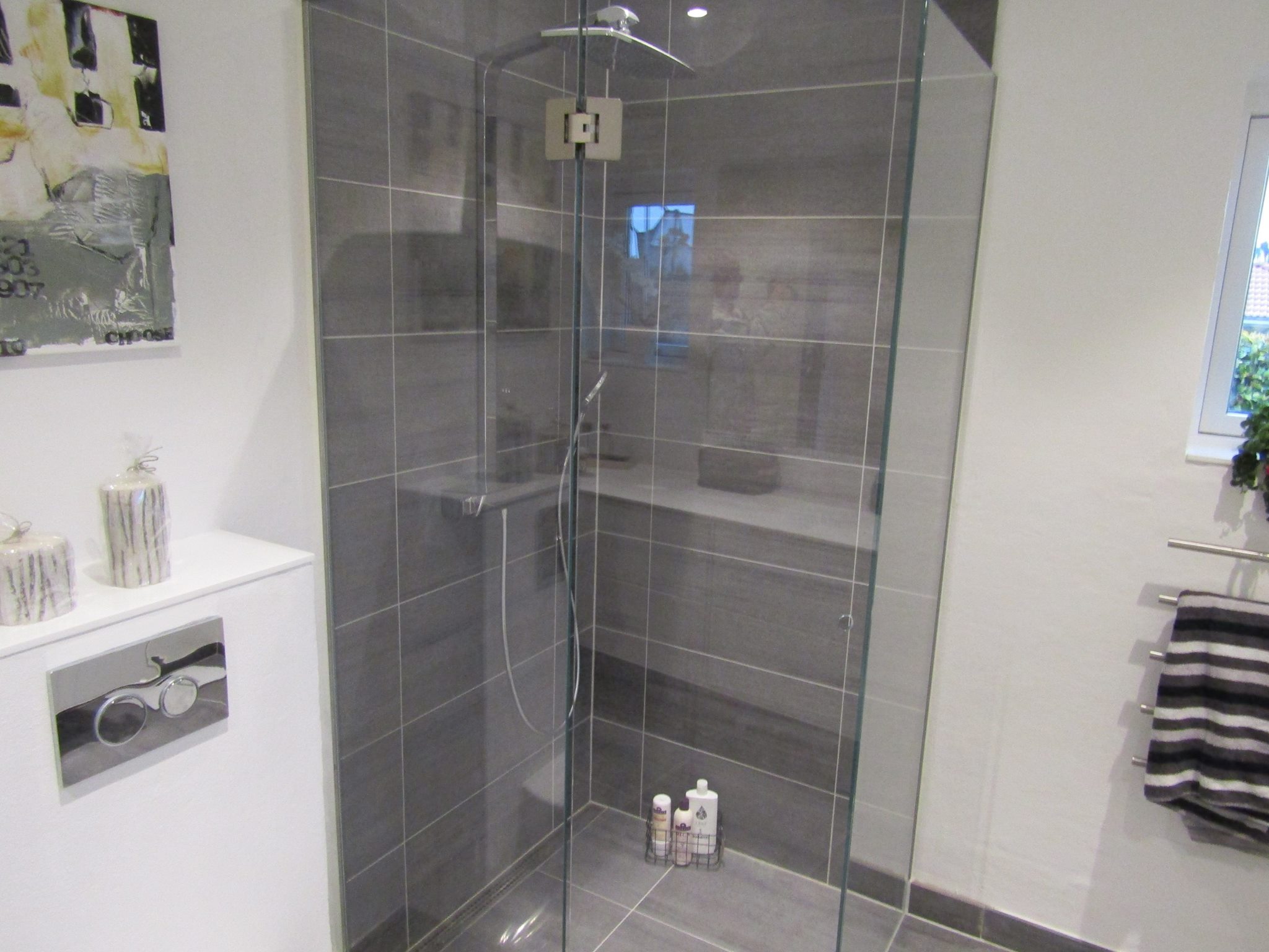 Brusehjørne med store grå væg- og gulvfliser og glasvæg, der viser moderne og præcis opsætning af klinker.