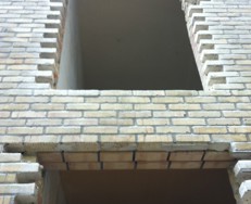 Murværk i gule tegl med ny, rå åbning til vindue eller dør – detalje fra facade under ombygning.