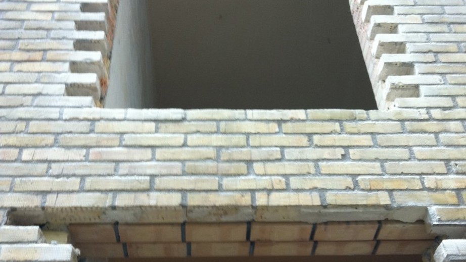 Murværk i gule tegl med ny, rå åbning til vindue eller dør – detalje fra facade under ombygning.