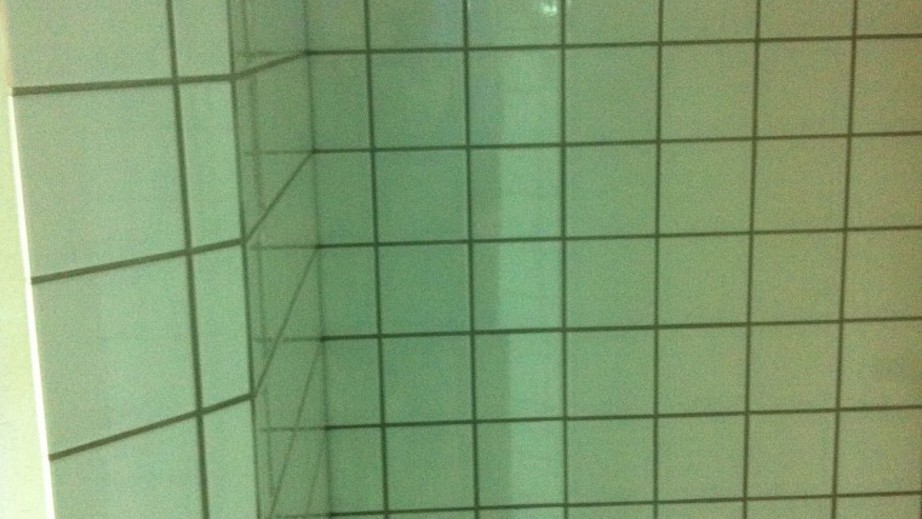 Niche på badeværelse med hvide kvadratiske vægfliser lagt i lige mønster.