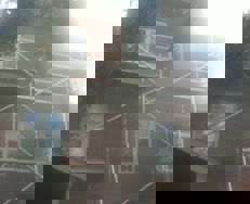 Murstenshus med opstillet facadestillads under renovering, set udefra i modlys.