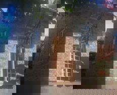 Renoveret murstenshus med pudset sokkel og store vinduer - set fra siden i sollys.