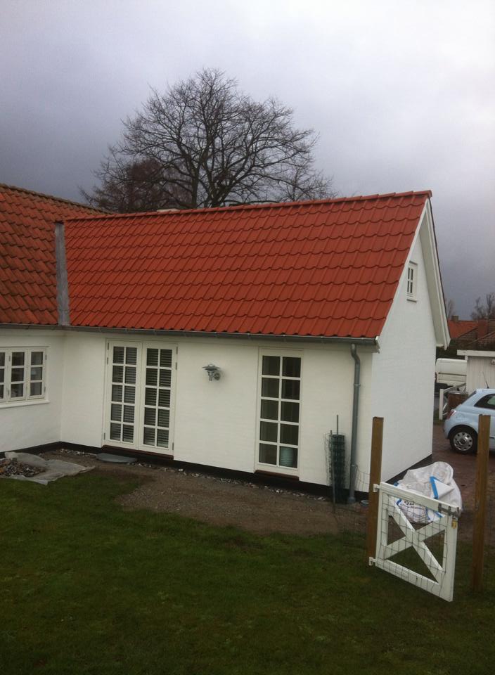 Et nyt renoveret tegltag på et hvidt hus.