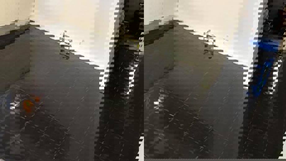 Køkken under renovering med nylagt blankt sort klinkegulv ved siden af eksisterende trægulv.